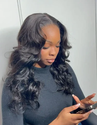 Une femme noire porte un tissage closure bouclé . Elle est chez une coiffeuse afro pas chère dans le 95 à côté de Paris.